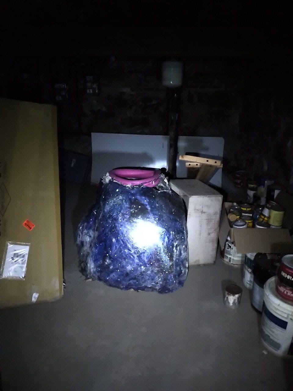 a blue object in a dark basement with a flashlight reflecting off of it