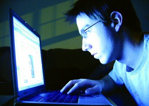 Man in dark room looking at computer screen